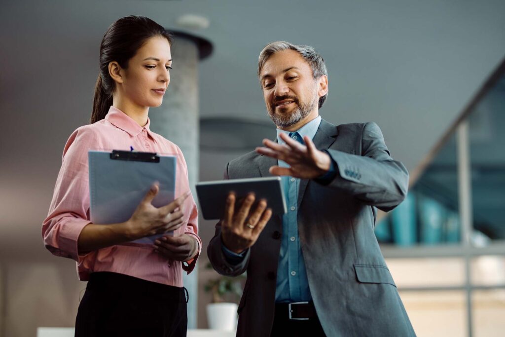 Two business colleagues working on digital tablet while standing
