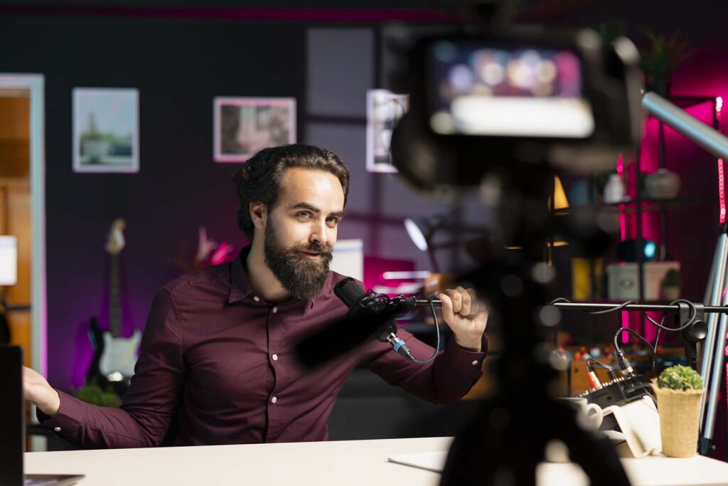 Influencer in rgb lit studio preparing microphone for vlog shooting