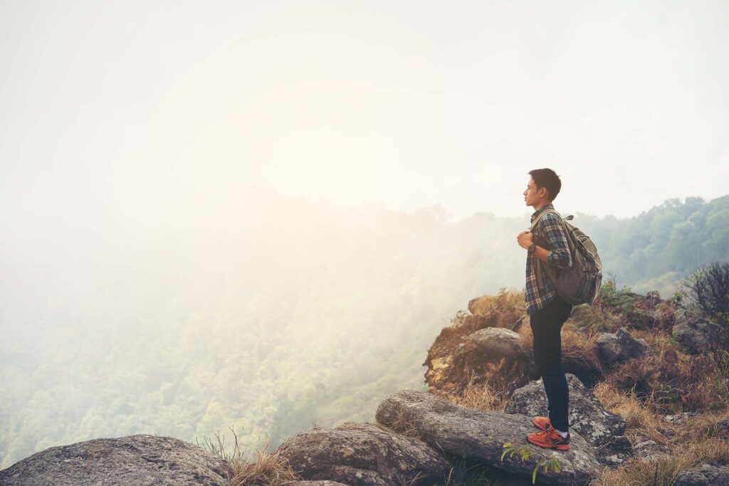Man traveler with backpack on top of mountain. Travel Lifestyle