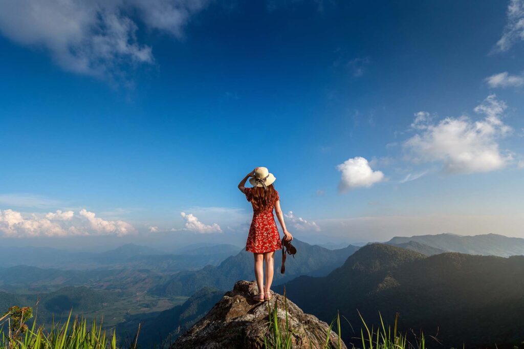 Woman hand holding camera and standing on top of the rock in nat